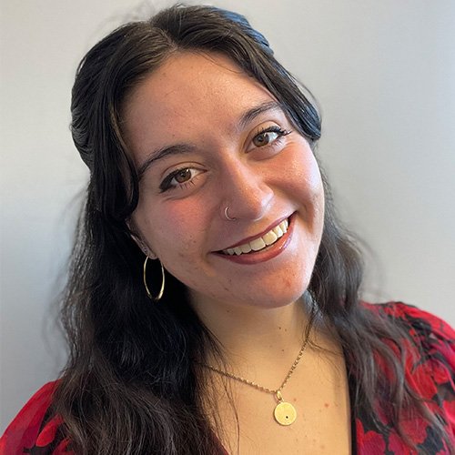 A headshot of a woman with dark hair and a red blouse, smiling warmly at the camera.
