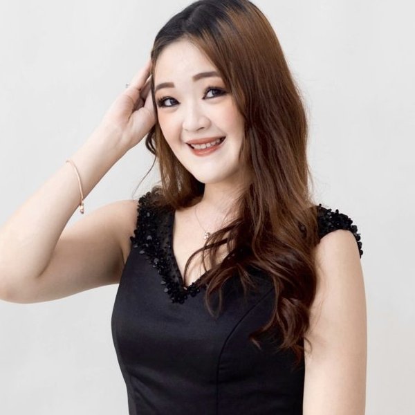An Asian woman with long hair in a black dress against a white background