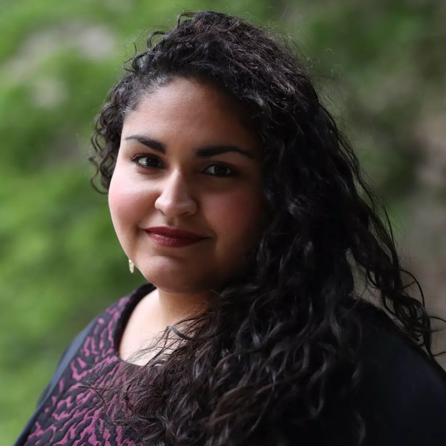 A headshot of a Puerto Rican woman with long wavy hair, smiling at the camera.