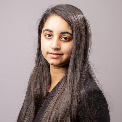 A woman with long dark hair, smiling softly at the camea.
