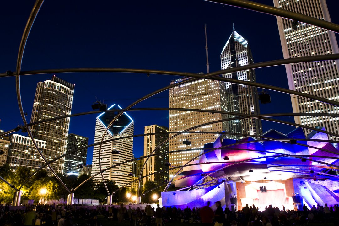 Jay Pritzker Pavilion with backdrop of Chicago skyline at night