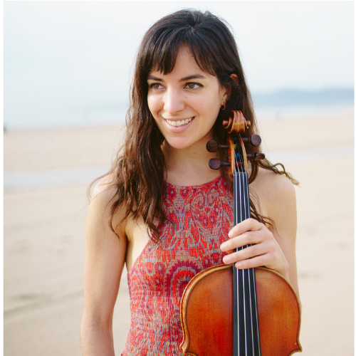 A young woman with long brown hair wearing a patterned red dress holds a viola
